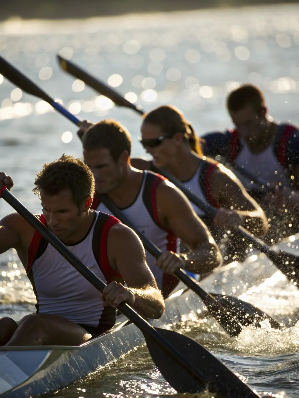 A team of rowers practicing on the lake at Lastioules, with synchronized movements and focused expressions. The image captures the discipline and teamwork involved in rowing.