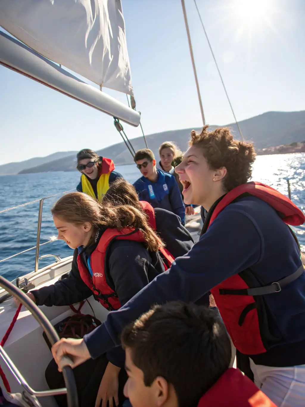 A group of children learning to sail on a small sailboat at Lastioules, with an instructor guiding them. The scene is sunny and cheerful, emphasizing the fun and educational aspects of the sailing program.